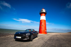 Fiat 124 Spider vor einem Leuchtturm